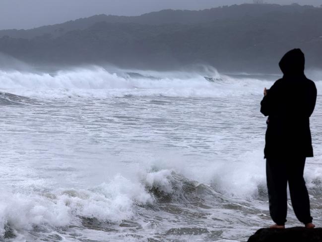 A resident watches massive waves stirred by tropical cyclone Alfred at Byron Bay's Main Beach on March 5, 2025. A rare tropical cyclone veered towards Australia's densely populated eastern coast on March 5, forcing scores of schools to close as worried residents stripped supermarket shelves bare. (Photo by David GRAY / AFP)