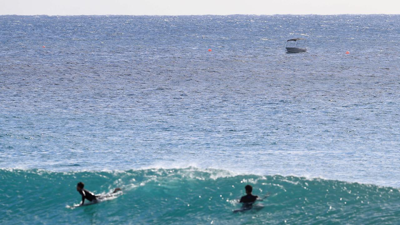 Two surfers enjoying the swell with Django’s boat in the distance. Photo: Adam Head