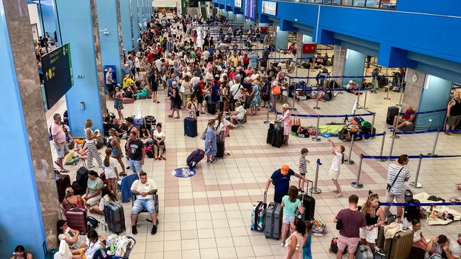 Tourists wait in the airport's departure hall as evacuations continue. (Photo by Will VASSILOPOULOS / AFP)