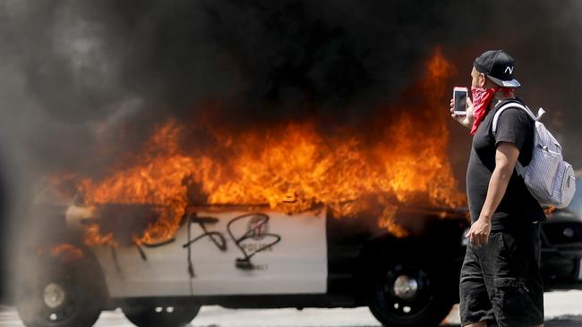 An LAPD vehicle burns after being set alight by protesters on Saturday.