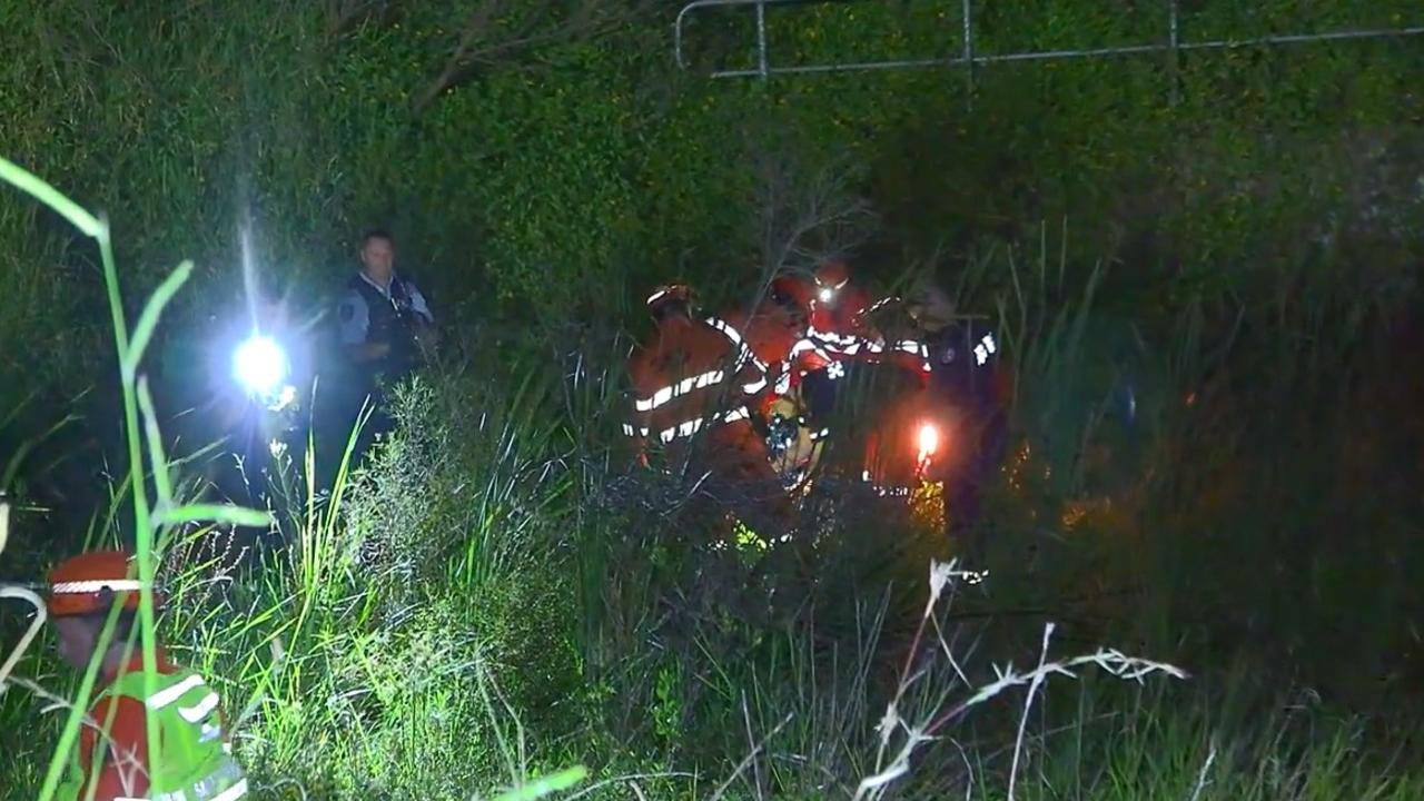 Emergency service personnel help a man after a crash that happened in an exit lane from the Pacific Highway at Moonee Beach on March 9, 2022.