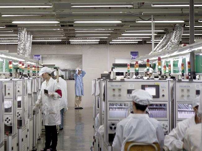 Employees of Hon Hai Precision Industry Co. Ltd. work along a production line in the Longhua Science and Technology Park, also known as Foxconn City, in Shenzhen, China, on Saturday, Sept. 4, 2010. Foxconn Technology Group Chairman Terry Gou cut his long-term growth target for the world's largest contract manufacturer of electronics by 50 percent as demand for Apple Inc. iPhones and iPads fails to offset slowing computer sales. Photographer: Thomas Lee/Bloomberg