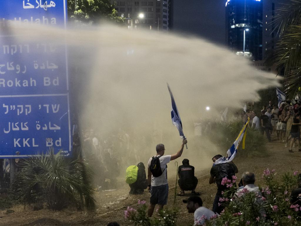 Protesters stand in water as police officers spray water cannon while trying to disperse protesters blocking a main highway. Picture: Amir Levy/Getty Images