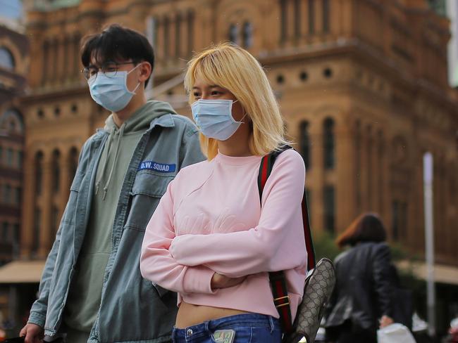 People wearing face masks as a preventative measure against coronavirus COVID-19 carry shopping bags as they walk in front the Queen Victoria Building in Sydney, Sunday, March 15, 2020. Prime Minister Scott Morrison has warned all Australians they could face more changes to their day-to-day lives to try curb the spread of COVID-19. (AAP Image/Steven Saphore) NO ARCHIVING