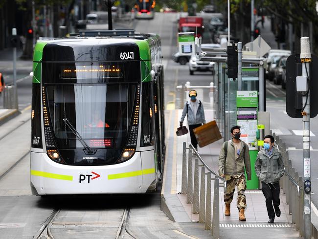 People wearing face masks as a preventive measure against Coronavirus are seen after disembarking a tram in Melbourne, Monday, April 6, 2020. Stage three social distancing measures are now in force throughout Victoria. (AAP Image/James Ross) NO ARCHIVING