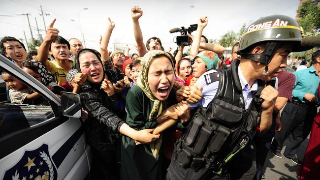 A United Nations report has China responsible for “serious human rights violations” in Xinjiang province. Ethnic Uygur women grab a riot policemen as they protest in Urumqi in China's far west Xinjiang province on July 7, 2009. Picture: PETER PARKS / AFP.