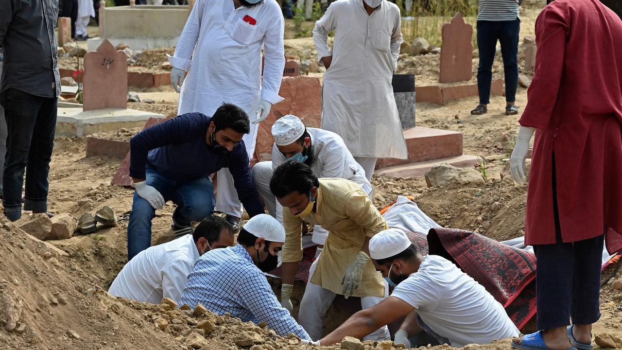 Relatives and friends lower the dead body of a coronavirus victim into a New Delhi grave. Picture: AFP.