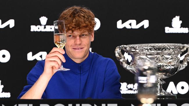 Jannik Sinner raises his glass to toast during a press conference following his Australian Open triumph. Photo by Vince CALIGIURI / TENNIS AUSTRALIA / AFP.