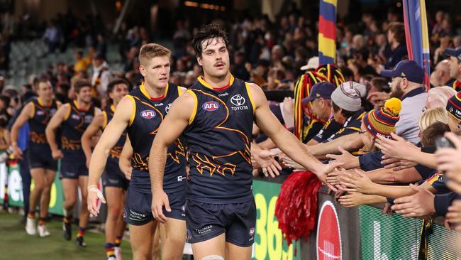 Darcy Fogarty of the Crows and teammates high-five fans after the Gather Round win. Picture: Sarah Reed/AFL Photos via Getty Images