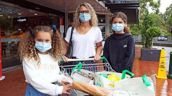 Kathryn Vaux and her daughters Scarlett, 11, and Sofia, 9, wear masks while shopping. Picture: Tim Hunter