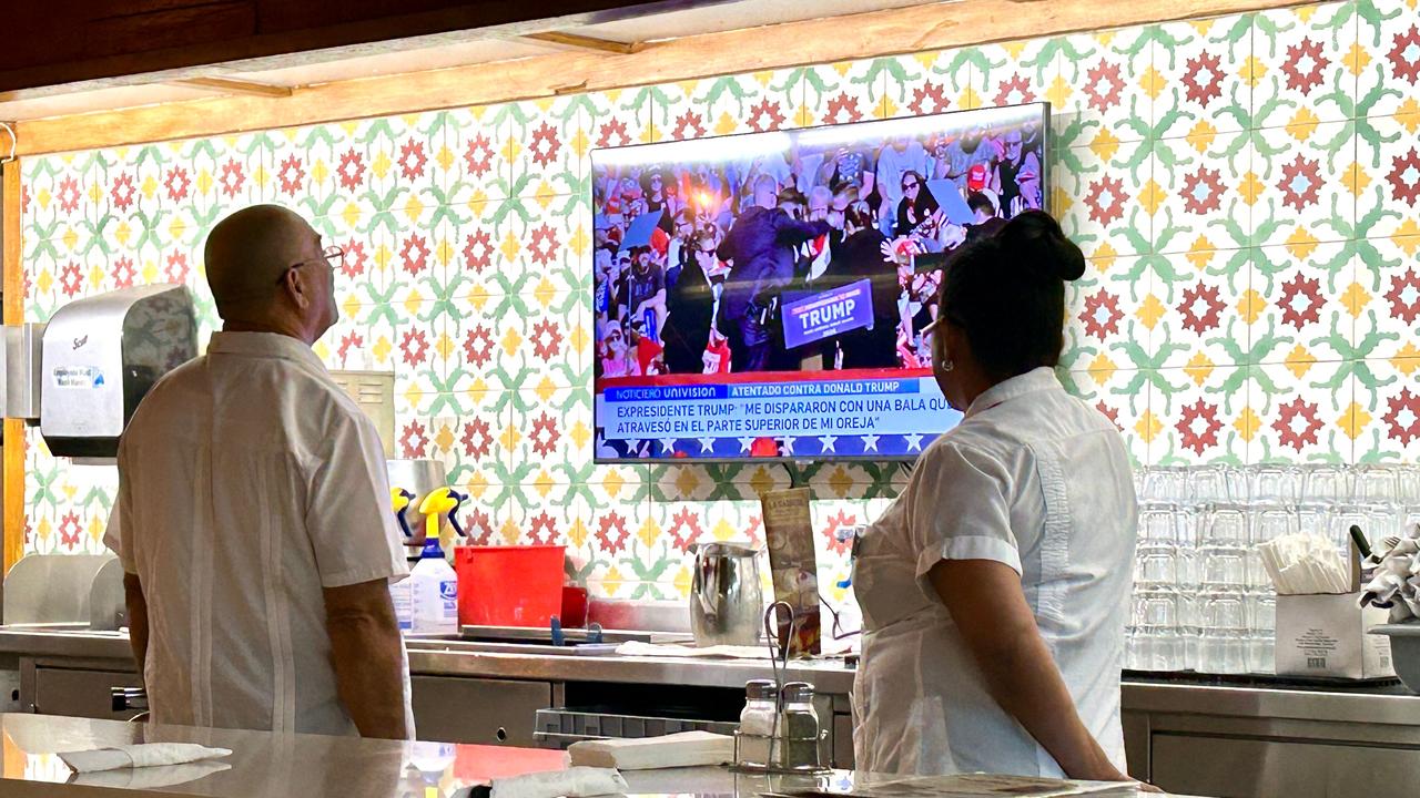 Employees in a Florida restaurant watch the news after hearing that Donald Trump was evacuated from the stage after shots were fired. Picture: Timothy Clary / AFP