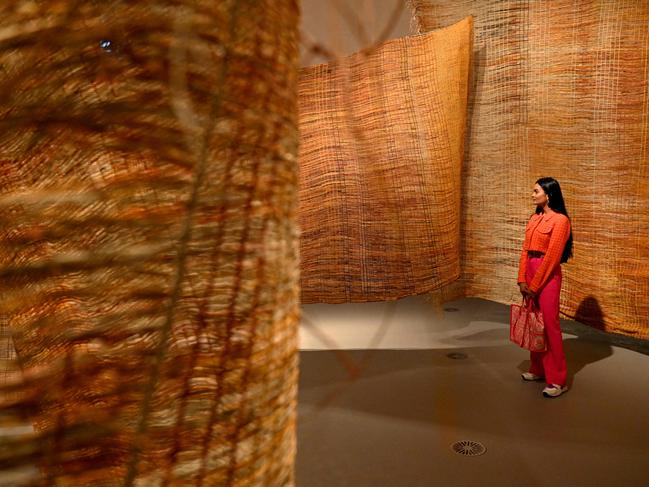 A woman inspects a 100m woven fish fence made by artists in Maningrida, on show at the NGV Triennial. Picture: William West/AFP