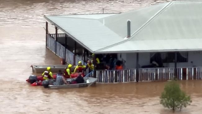 This frame grab taken from video footage provided by The Queensland Fire Department on March 28, 2025 via AFPTV shows rescue workers taking residents from a house on a flooded street in the town of Adavale in south-west Queensland. Whole herds of cattle have drowned in vast inland floods seeping across the Australian outback, officials said on April 1 as the muddy tide drenched an area the size of France. (Photo by Handout / QUEENSLAND FIRE DEPARTMENT / AFP)
