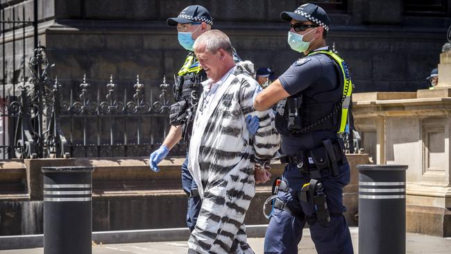 Another man is led away in handcuffs. Picture: Jake Nowakowski