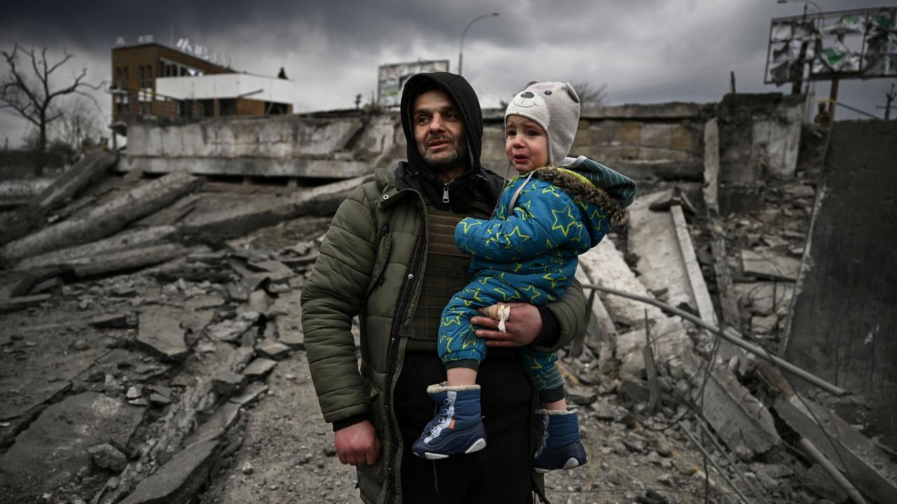 A man holds a child as he flees the city of Irpin, west of Kyiv. Picture: Aris Messinis/AFP