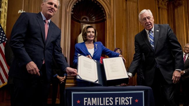 House Speaker Nancy Pelosi, centre, Minority Leader Kevin McCarthy, left, and Majority Leader Steny Hoyer hold up the legislation enacting the $US2.2 trillion coronavirus rescue package. Picture: AP