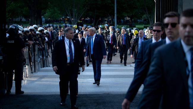 US President Donald Trump walks through a colonnade of police in riot gear while walking to the White House from St. John's Church after the area was cleared of people protesting the death of George Floyd.