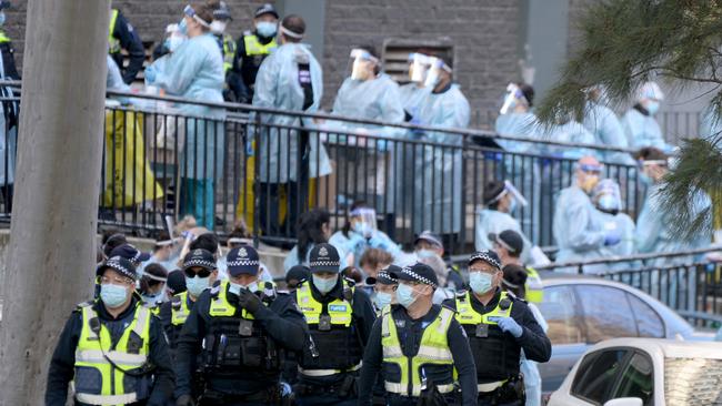 Police and healthcare workers prepare to enter one of the towers at the North Melbourne public housing estate. Picture: Andrew Henshaw