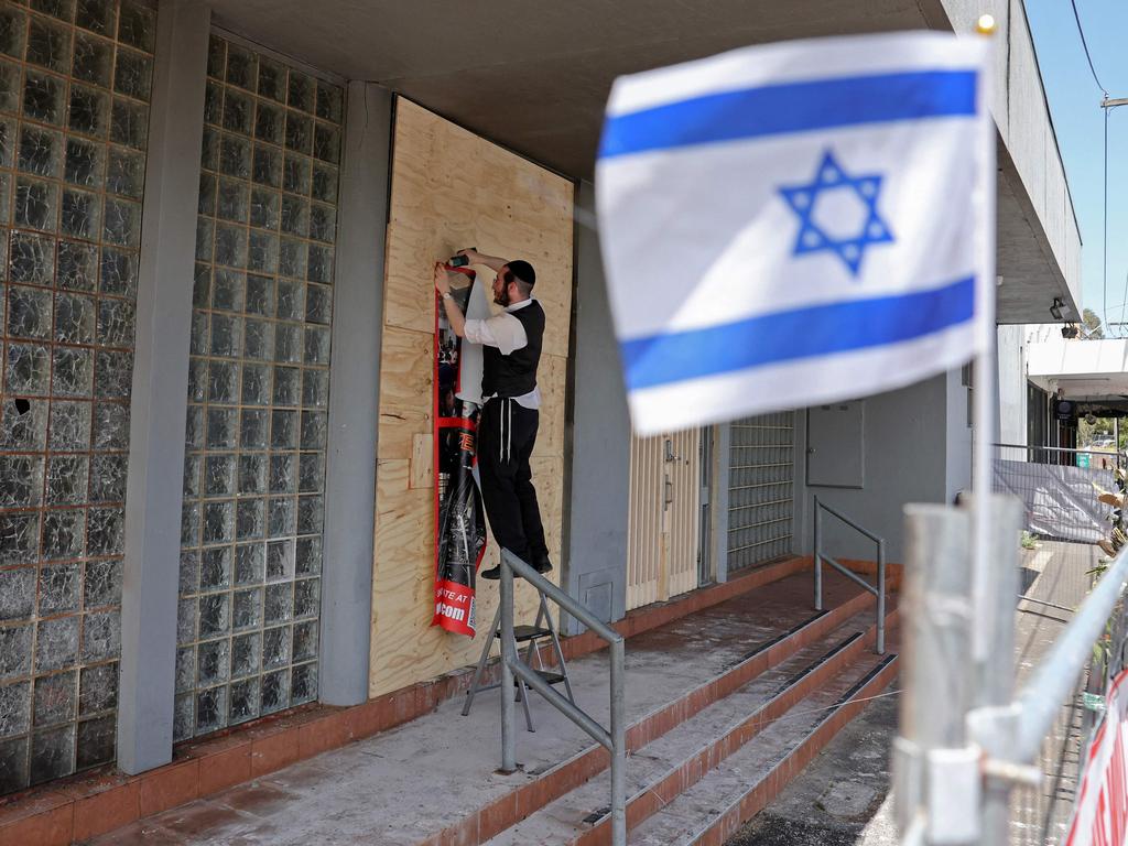 A member of the Jewish community staples a poster to the front of the damaged synagogue. Picture: AFP