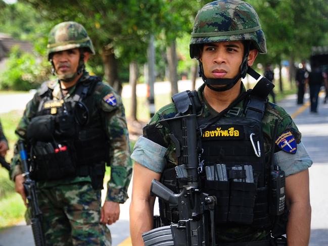 Thai soldiers watch as a forensic unit inspects the scene of an attack following two roadside bomb blasts at four separate locations by suspected separatist militants in the Bacho district of Thailand's restive southern province of Narathiwat on August 15, 2016. Several soldiers were injured in the attack. More than 6,500 people have been killed -- the majority civilians -- since 2004 in clashes between militants and security forces from Thailand's Buddhist-majority state. / AFP PHOTO / MADAREE TOHLALA