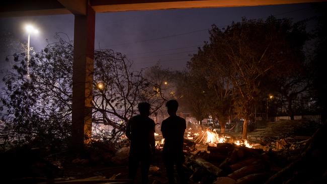 NEW DELHI, INDIA – APRIL 29: Funeral pyres can be seen burning as people perform the last rites for relatives who have lost their lives to COVID-19 on April 29, 2021 in New Delhi, India. With recorded cases crossing 380,000 a day and 3000 deaths in the last 24 hours, India has more than 2 million active cases of COVID-19, the second-highest number in the world after the U. S. A new wave of the pandemic has totally overwhelmed the country's healthcare services and has caused crematoriums to operate day and night as the number of victims continues to spiral out of control. (Photo by Anindito Mukherjee/Getty Images)