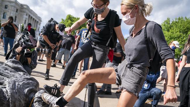 People take turns kicking the Christopher Columbus statue after it was toppled in front of the Minnesota State Capitol. Picture: Leila Navidi/Star Tribune