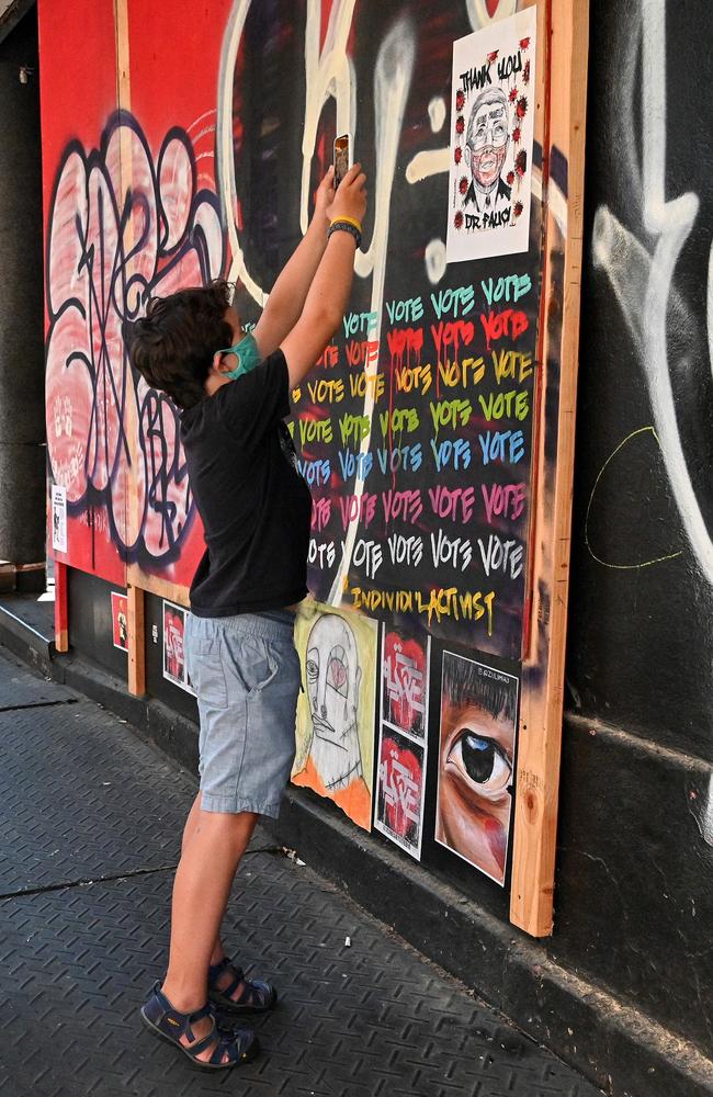 A young man wearing a protective mask takes a photo of a sign reading "Thank You Dr. Fauci" in the Nolita neighbourhood of Manhattan as the city continues Phase 4 of reopening following restrictions imposed to slow the spread of coronavirus. Picture: Getty