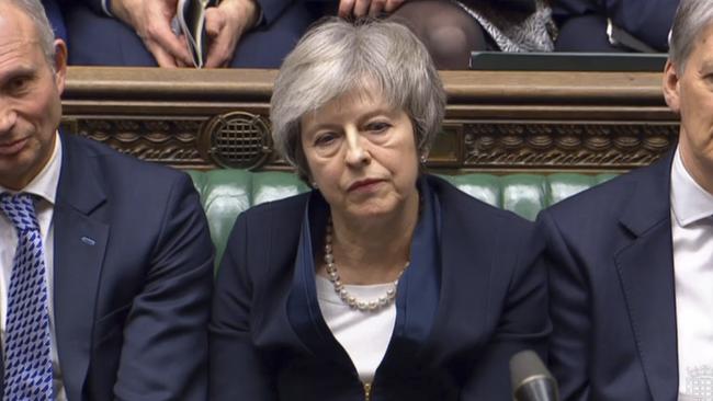 British Prime Minister Theresa May listens to Labour leader Jeremy Corbyn speaking after losing a vote on her Brexit deal.