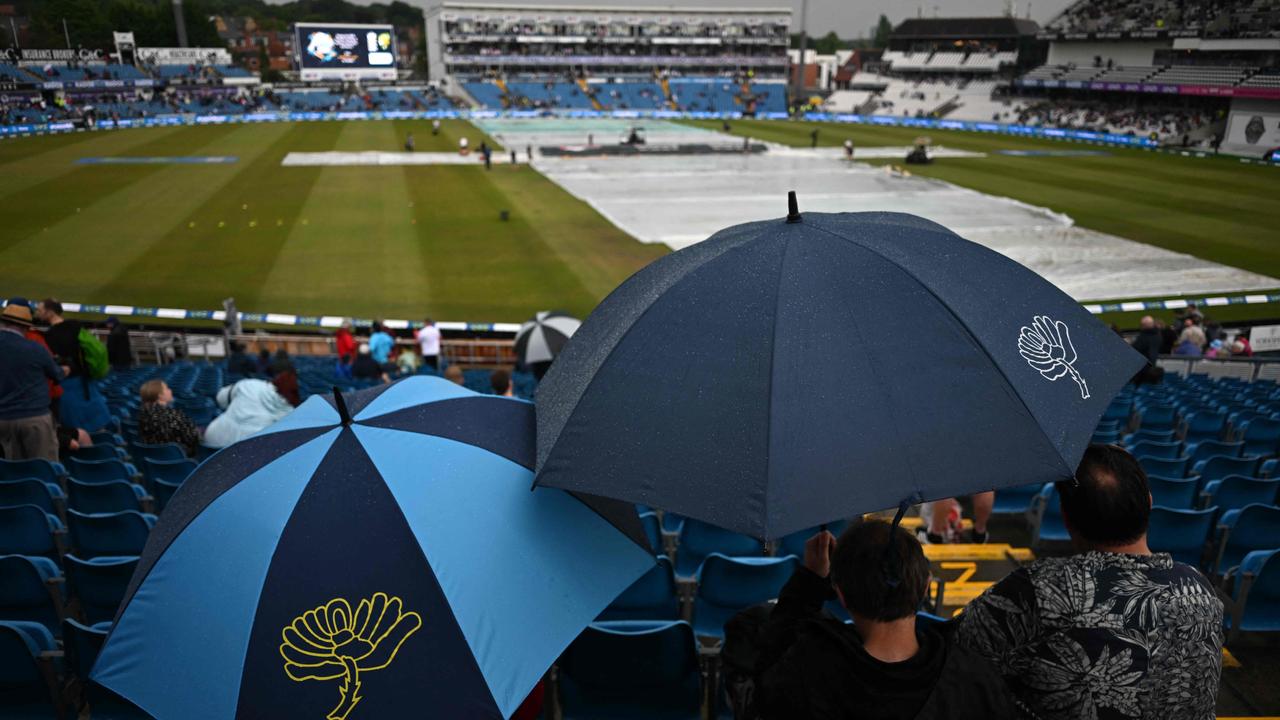 Spectators shelter under umbrellas as the rain delays the start of play on day three. Picture: AFP