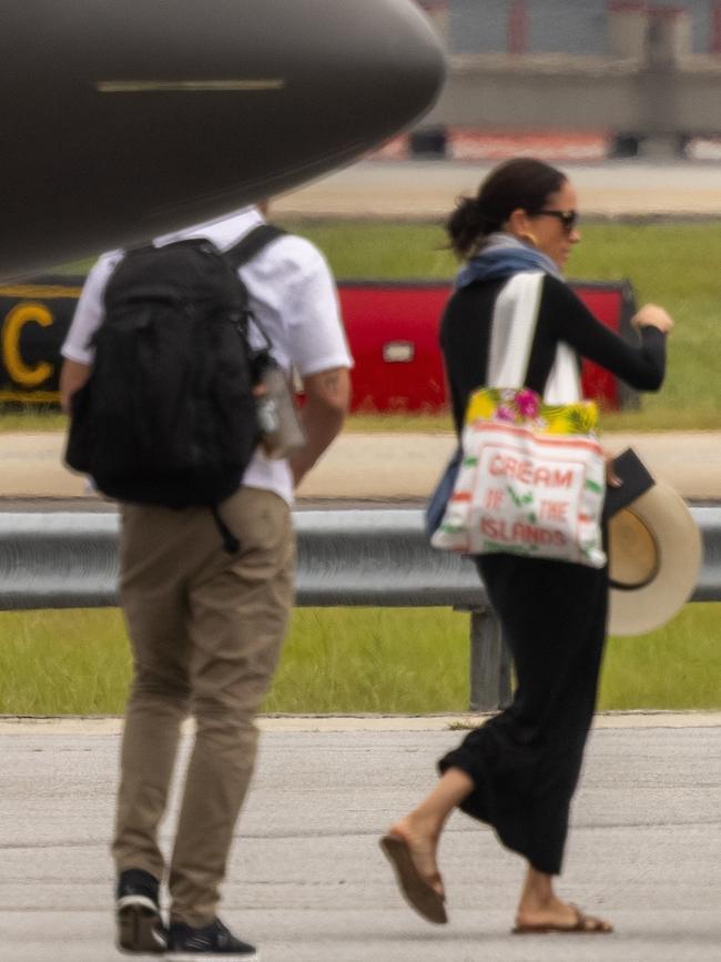 Meghan was pictured with him, holding an over-size hat and a large tote bag. Picture: