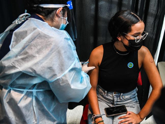 A health care worker administers a Covid-19 vaccine to 15-year-old Valentina Jimenez during a vaccination event hosted by Miami Heat at FTX Arena in Miami, on August 5, 2021. (Photo by CHANDAN KHANNA / AFP)