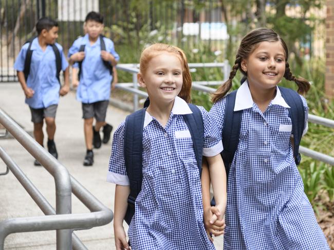 Female primary school students wearing blue gingham dresses with boys in background Picture: Istock