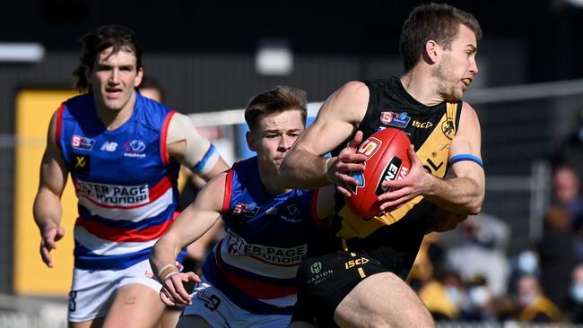 Glenelg’s Chris Curran looks to escape the tackle. Picture: Naomi Jellicoe