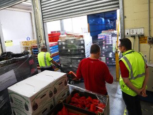 Coles truck drivers unload perishable goods into the Batemans Bay store, as getting food to people in evacuation zones becomes a critical issue. Picture: John Grainger