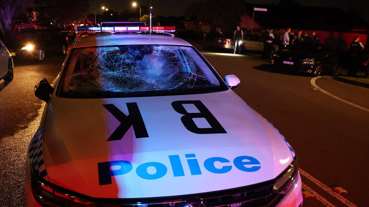 A damaged police car is seen after a mob was pushed back by police outside the Christ the Good Shepherd Church in Sydney's western suburb of Wakeley after several people were stabbed. Picture: AFP