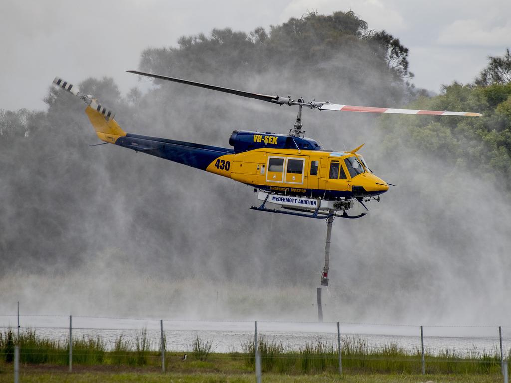 Smoke haze covers the Gold Coast Skyline from a grass fire at Carrara. A firefighting helicopter collects water from Judy Turners property in Carrara . Picture: Jerad Williams