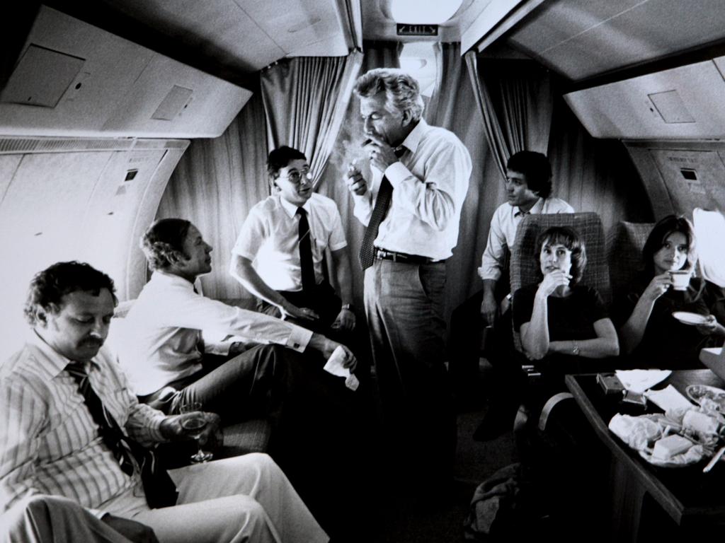 New Labor and Oppostion leader Bob Hawke surrounded by advisors and media (L-R) journalist Colin Parks, Senator Kerry Sibraa, journalist Peter Logue, senior advisor Geoff Walsh, staffers Kate Moore and Janet Willis, lights up a cigar on a VIP flight during the 1983 Federal Election Campaign, which saw Labor swept to a landslide victory. Picture: Ray Strange