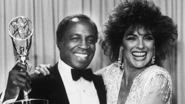 FILE - In this Sept. 22, 1985 file photo, actor Robert Guillaume, star of "Benson", gets a hug from Linda Gray of "Dallas" who presented him with the Emmy for outstanding lead actor in a comedy series, in Pasadena, Calif.  Guillaume, who won Emmy Awards for his roles on â€œSoapâ€ and â€œBenson,â€ died Tuesday, Oct. 24, 2017 in Los Angeles at age 89. Guillaumeâ€™s widow Donna Brown Guillaume says he had been battling prostate cancer. (AP Photo/File)