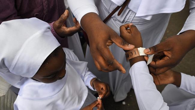 Members of the Brotherhood Of The Cross &amp; Star Church in Elephant and Castle neighbourhood put their wristband as they join the queue in Southwark Park.