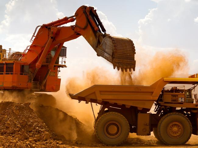 A haul truck is loaded by a digger with material from the pit at Rio Tinto Group's West Angelas iron ore mine in Pilbara, Australia, on Sunday, Feb. 19, 2012. Rio Tinto Group, the world's second-biggest iron ore exporter, will spend $518 million on the first driverless long-distance trains to haul the commodity from its Western Australia mines to ports, boosting efficiency. Photographer: Ian Waldie/Bloomberg via Getty Images