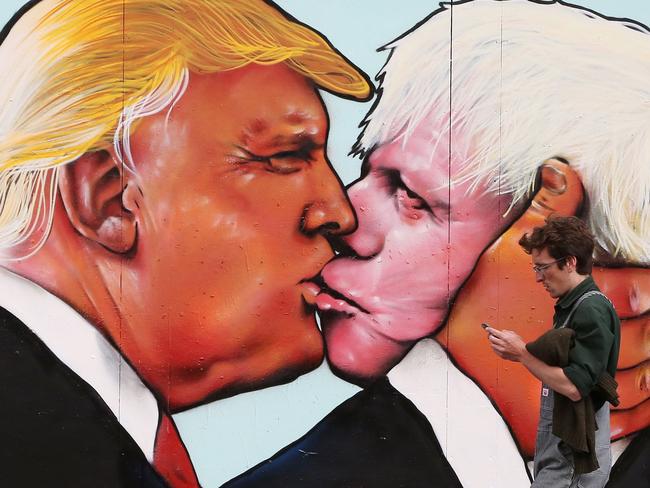 TOPSHOT - A man walks past a mural showing likely US Republican presidential nominee Donald Trump (L) kissing the Former Mayor of London and Conservative MP, Boris Johnson, on the side of a building in Bristol, south west England on May 24, 2016. The mural in Bristol, southwest England, was commissioned by We Are Europe, a campaign group which wants Britain to remain in the European Union at the June 23 vote. / AFP PHOTO / GEOFF CADDICK / RESTRICTED TO EDITORIAL USE - MANDATORY MENTION OF THE ARTIST UPON PUBLICATION - TO ILLUSTRATE THE EVENT AS SPECIFIED IN THE CAPTION