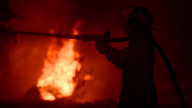 A Rural Fire Service firefighter conducts mopping up near the town of Sussex Inlet on New Year’s Eve. Picture: Getty Images