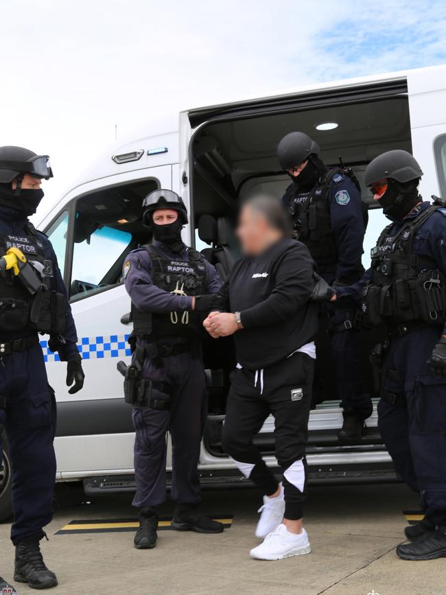 Sam Ibrahim is accompanied out of a NSW Police van at Sydney airport of Thursday morning. Picture: NSW Police