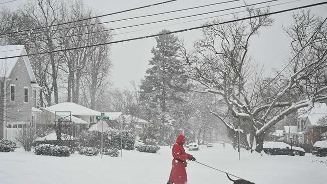 TOPSHOT - A pedestrian crosses the street as snow falls during a winter storm in Bethesda, Maryland on January 6, 2025. A massive storm system dumped heavy snow and freezing rain on large swaths of the eastern United States Monday, disrupting travel and work for millions of Americans from the Ohio Valley to the capital Washington. (Photo by PEDRO UGARTE / AFP)