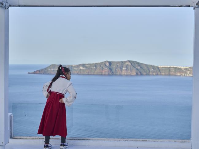 A woman from China looks on from a caldera at Firostefani, as in the background stands the island of Therasia. Picture: AP