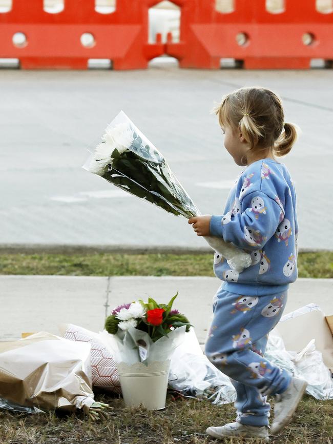 A young girl leaves a floral tribute near the scene of the crash. Picture: Jonathan Ng