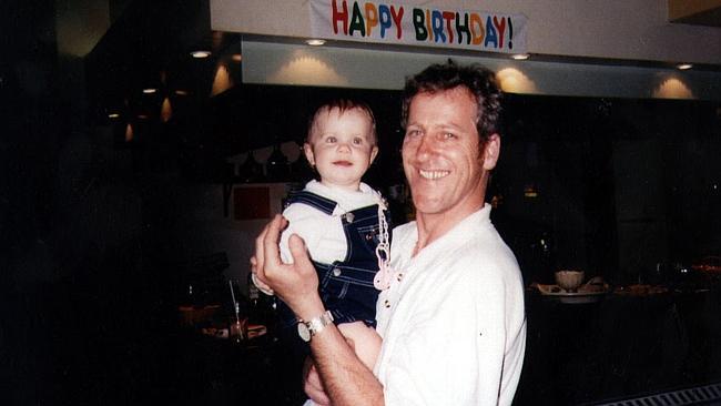 Laura Folbigg, one of four children that died, pictured with her father Craig at her first birthday party. 