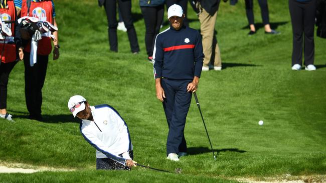 Former US Secretary of State Condoleezza Rice plays a bunker shot watched by Kelly Slater .