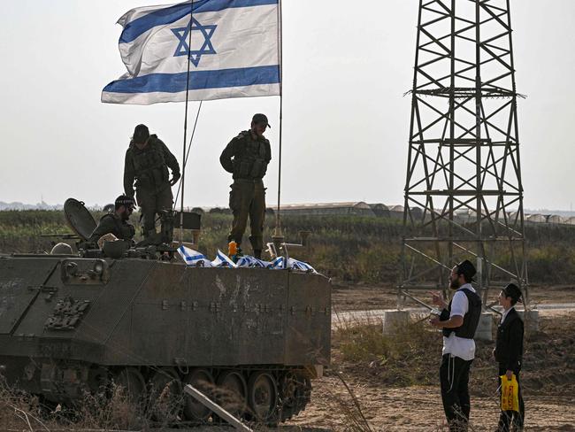 Israeli soldiers on an armoured vehicle speak an ultra Orthodox man, as they deploy near Israel's border with the Gaza Strip. Picture: AFP