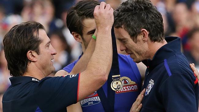 Luke Beveridge puts his premiership medal over injured then-captain Bob Murphy's neck as stand in captain Easton Wood looks on. Picture: Wayne Ludbey